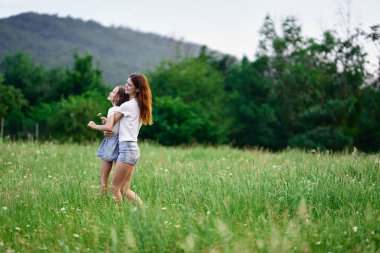 Genç anne ve kızı papatya tarlasında eğleniyorlar.