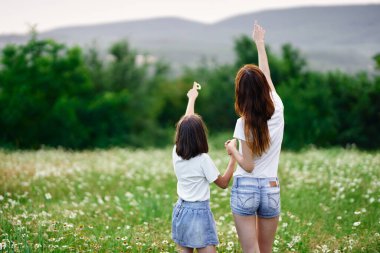Genç anne ve kızı papatya tarlasında eğleniyorlar.