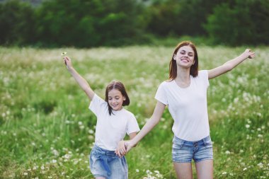Genç anne ve kızı papatya tarlasında eğleniyorlar.