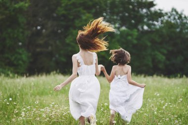 Genç anne ve kızı papatya tarlasında eğleniyorlar.