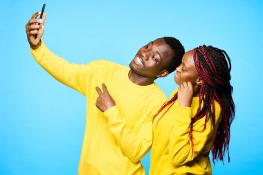 Genç ve güzel bir çift stüdyoda mavi arka planda selfie çekiyor.