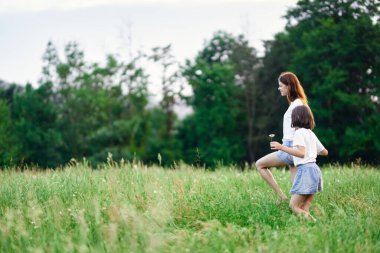 Genç anne ve kızı papatya tarlasında eğleniyorlar.