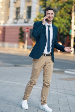 Genç yakışıklı işadamı sokakta akıllı telefondan konuşuyor. 