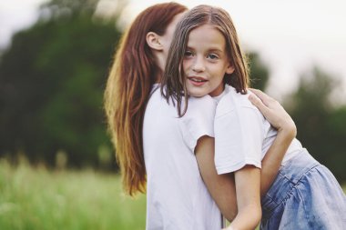 Genç anne ve kızı papatya tarlasında eğleniyorlar.