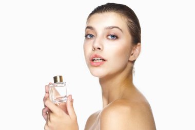 Genç ve güzel bir kadın parfüm şişesi tutuyor. Stüdyo çekimi 