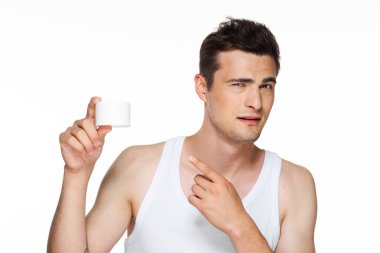 Stüdyo çekimi. Güzellik ürünleriyle kafası karışmış genç bir adam.