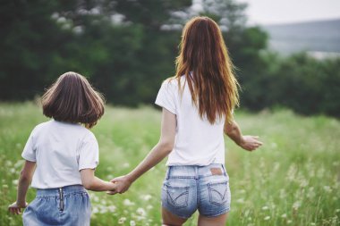 Genç anne ve kızı papatya tarlasında eğleniyorlar.