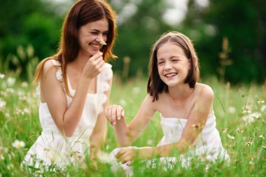 Genç anne ve kızı papatya tarlasında eğleniyorlar.