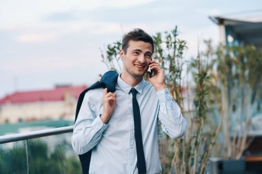 Genç yakışıklı işadamı sokakta akıllı telefondan konuşuyor. 
