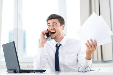 İş adamı elinde belgelerle ofisteki akıllı telefondan konuşuyor. 