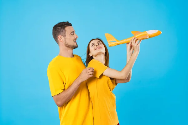 Jong Mooi Paar Spelen Met Geel Speelgoed Vliegtuig Blauwe Achtergrond — Stockfoto