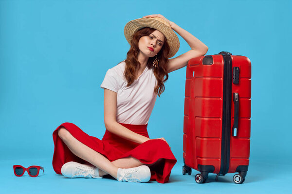 Young woman with red suitcase in studio