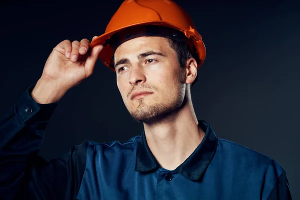 Studio shot. Young worker in orange helmet