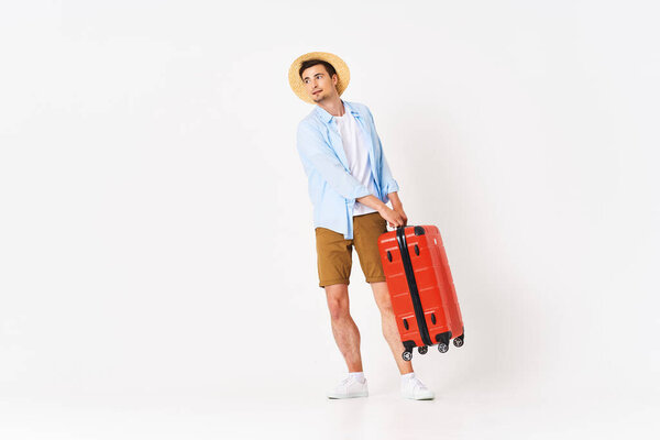 Young man with red suitcase in studio