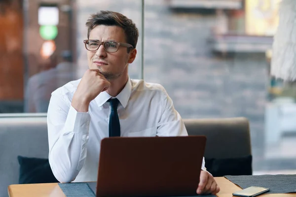 Young confused  businessman with laptop