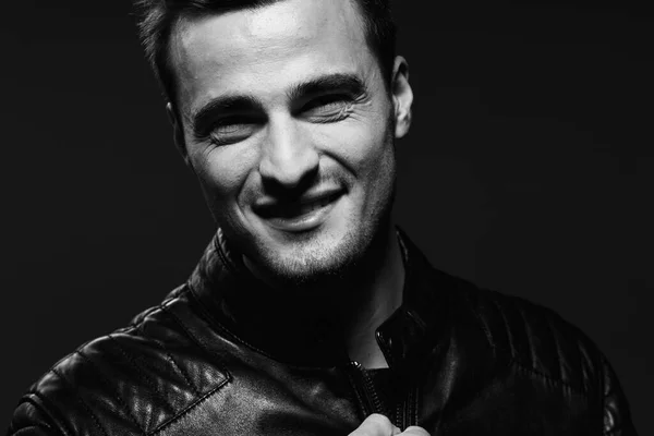 Young handsome man in leather jacket posing in studio. Black and white