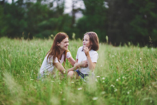 Young mother and her daughter having fun on camomile field
