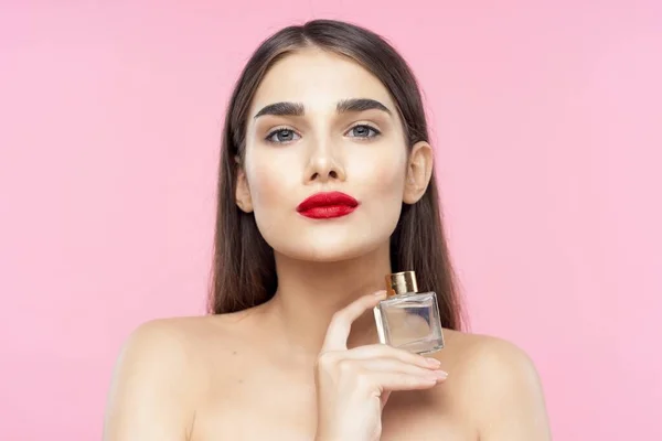 Portrait of young beautiful  woman with perfume bottle. Studio shot