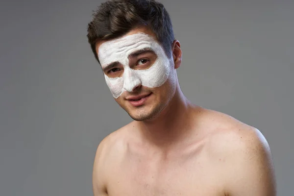 Young man applying facial mask