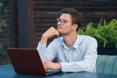 Kafede dizüstü bilgisayarla çalışan yakışıklı bir iş adamı.