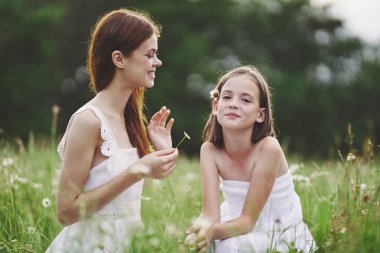 Genç anne ve kızı papatya tarlasında eğleniyorlar.