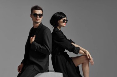 Siyah elbiseli genç çift stüdyoda poz veriyor.