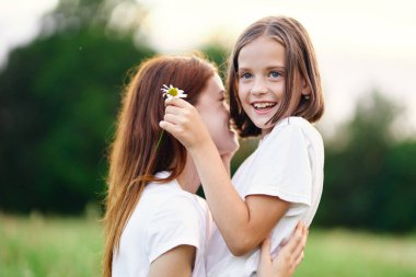 Genç anne ve kızı papatya tarlasında eğleniyorlar.
