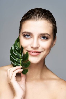 Stüdyoda yaprak ile poz veren genç güzel model.