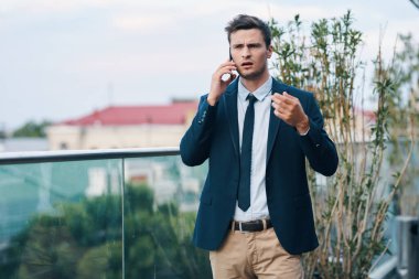 Genç yakışıklı iş adamı dışarıda akıllı telefon kullanıyor.
