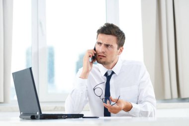 İş konsepti. Ofiste otururken Yong 'un kafası karışmış bir işadamı akıllı telefondan konuşuyor. 