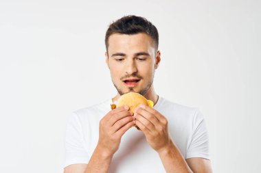 Stüdyoda hamburger yiyen genç adam. 
