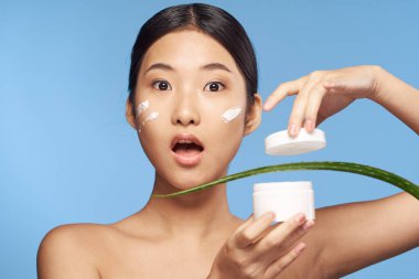 Genç güzel Asyalı kadın aloe vera yaprağıyla poz veriyor. 