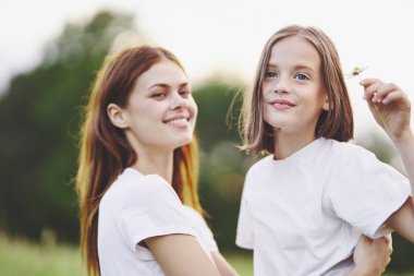 Genç anne ve kızı papatya tarlasında eğleniyorlar.