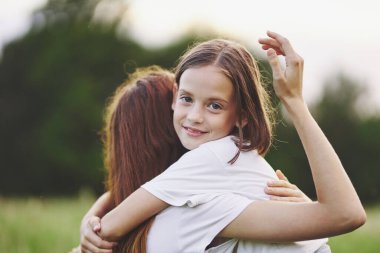 Genç anne ve kızı papatya tarlasında eğleniyorlar.