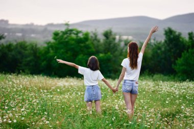 Genç anne ve kızı papatya tarlasında eğleniyorlar.