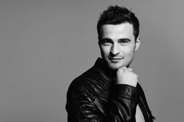 Stüdyoda poz veren siyah deri ceketli yakışıklı bir adamın portresi. Siyah ve beyaz  