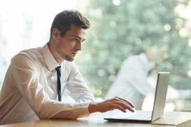 Genç iş adamı ofiste dizüstü bilgisayar kullanıyor. 