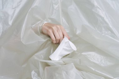Plastik ve polietilen yırtıklar olan bir kadın eli.