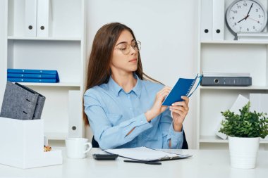 Ofisteki masada not defteriyle çalışan genç iş kadını.