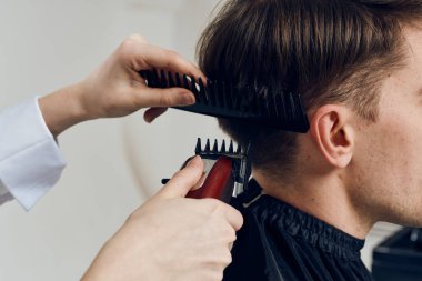 Genç bayan kuaför kuaförde müşterinin saçını kesiyor.          