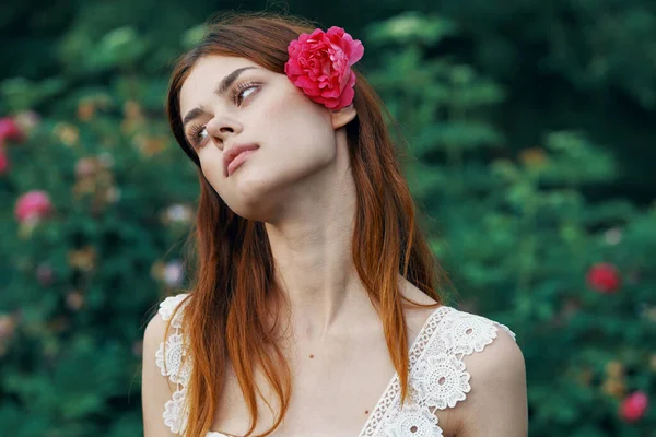 Young woman with rose flower in the garden