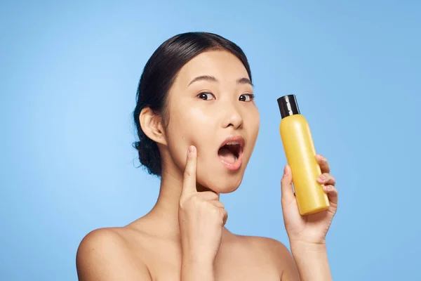 Young beautiful  confused asian woman  holding  lotion  isolated