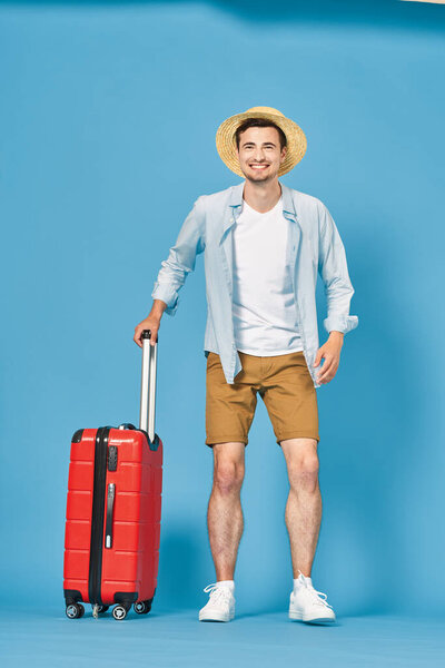 Young man with red suitcase in studio