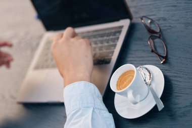 Kafede dizüstü bilgisayarla çalışan yakışıklı bir iş adamı.