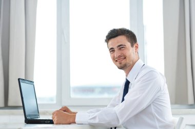 Ofisinde dizüstü bilgisayarı olan genç bir iş adamı. 