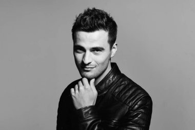 Stüdyoda poz veren deri ceketli yakışıklı bir genç. Siyah ve beyaz 