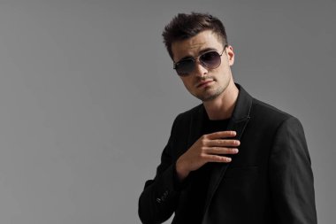 Stüdyo çekimi. Güneş gözlüğü takan genç yakışıklı adamın portresi.