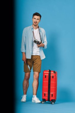 Stüdyoda kırmızı bavullu genç adam.