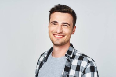 Stüdyoda gülümseyen genç adam, beyaz arka planda soyutlanmış.