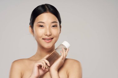 Stüdyo çekimi. Genç Asyalı kadın portresi ve güzellik ürünü.